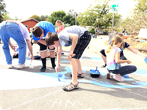 all ages painting the neighborhood street mural together