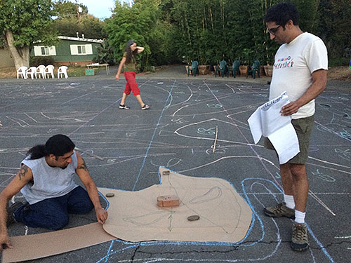 tracing stencils with chalk in preparation for painting street mural at intersection of M Street and Duke Drive in Davis, California